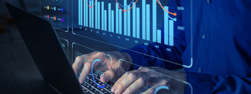 A person's hands working on a laptop in a dark room.